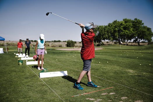 A group of youth practicing golf swings on a sunny day at the driving range.